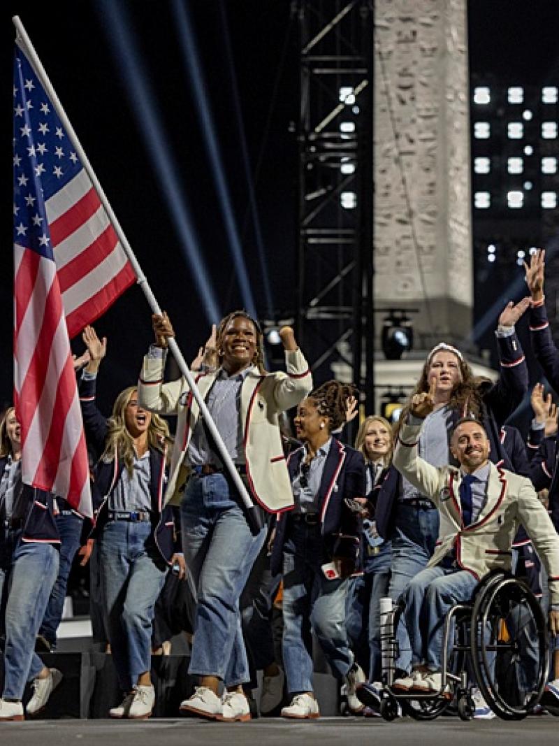 A group of athletes wearing a blue or white jacket are parading during the Opening Ceremony of Paris 2024